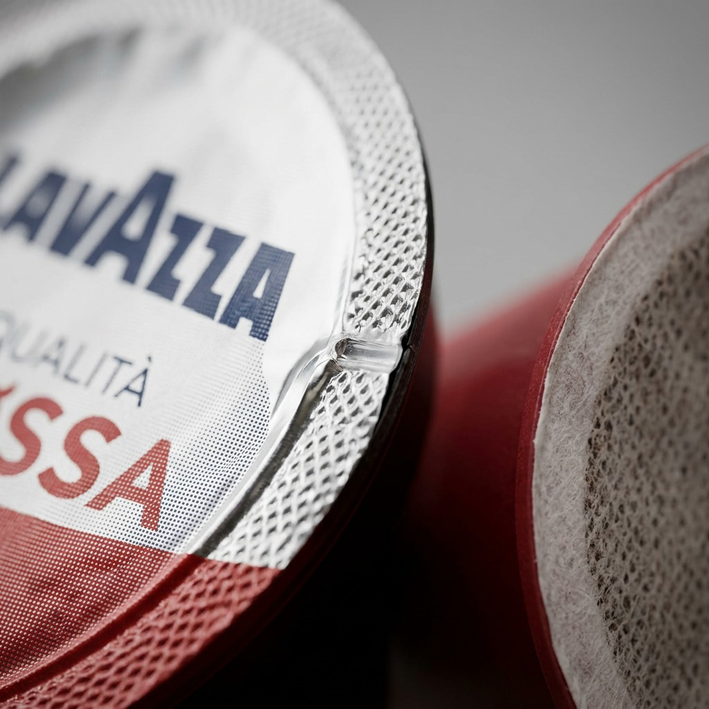 Extreme macro detail of a Lavazza Qualità Rossa K-Cup pod foil seal and textured rim.